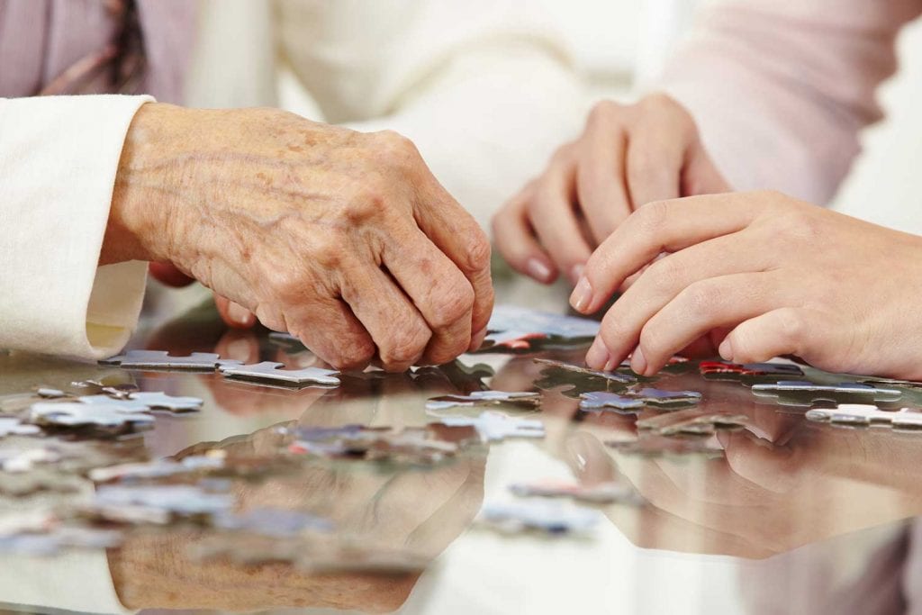 Close up shot of young and old hands doing a jigsaw puzzle.